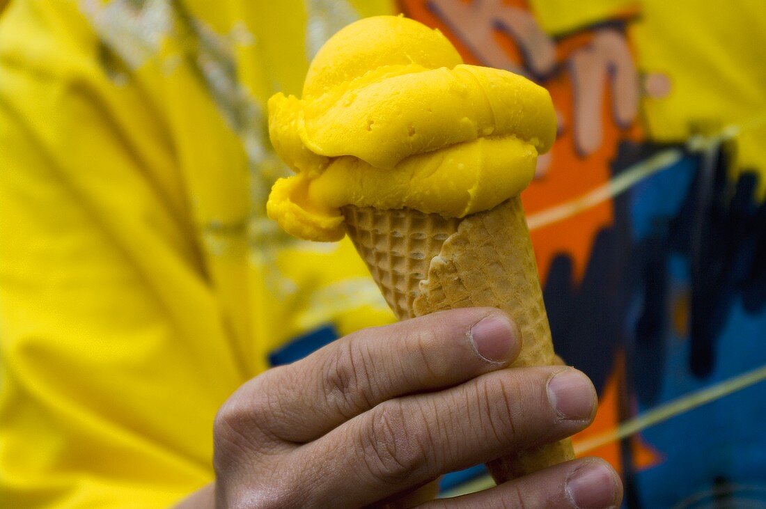 Mann hält eine Waffel mit Mangoeis in der Hand