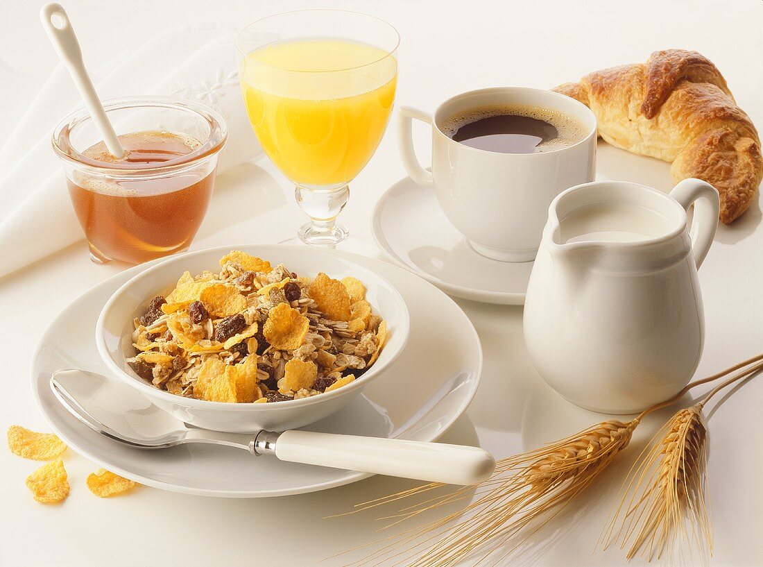 Frühstück mit Müsli, Honig, Orangensaft, Kaffee und Croissant