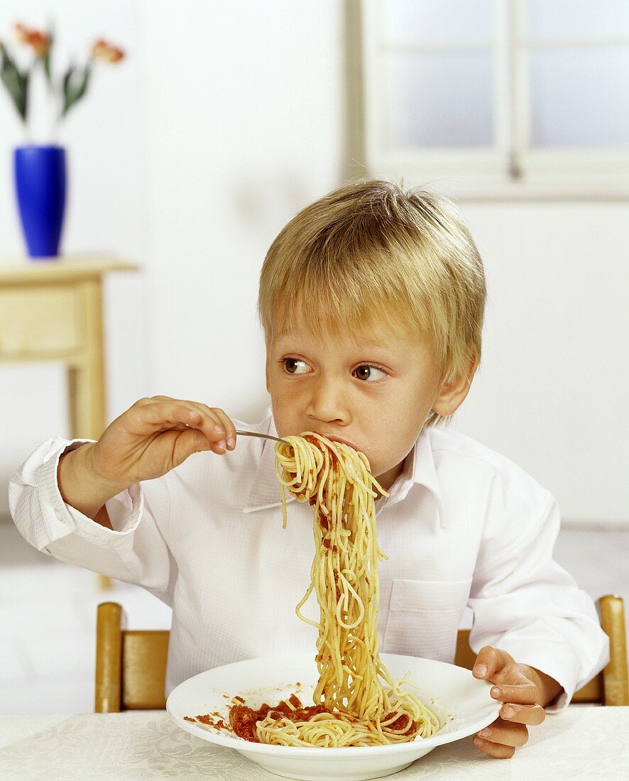 Junge isst Spaghetti mit Tomatensauce