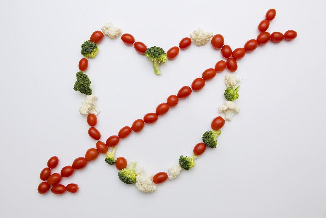 Tomatoes, broccoli and cauliflower forming heart with arrow
