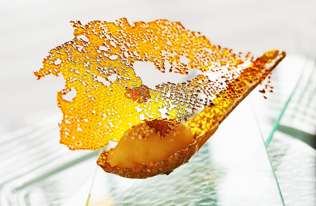 A mungo bean cake on a caramel spoon (Asia)