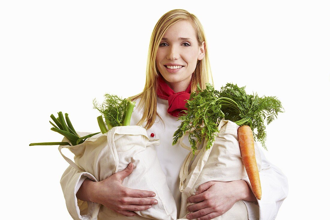 Blond chef holding two bags of vegetables