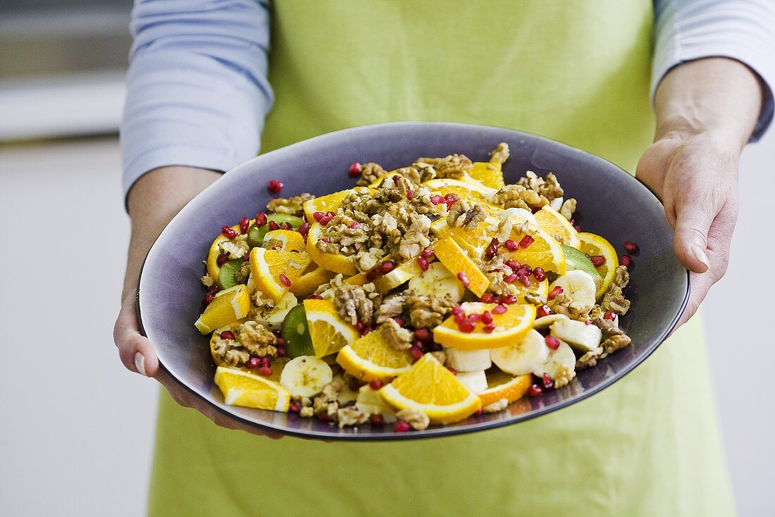 Woman serving fruit salad with walnuts