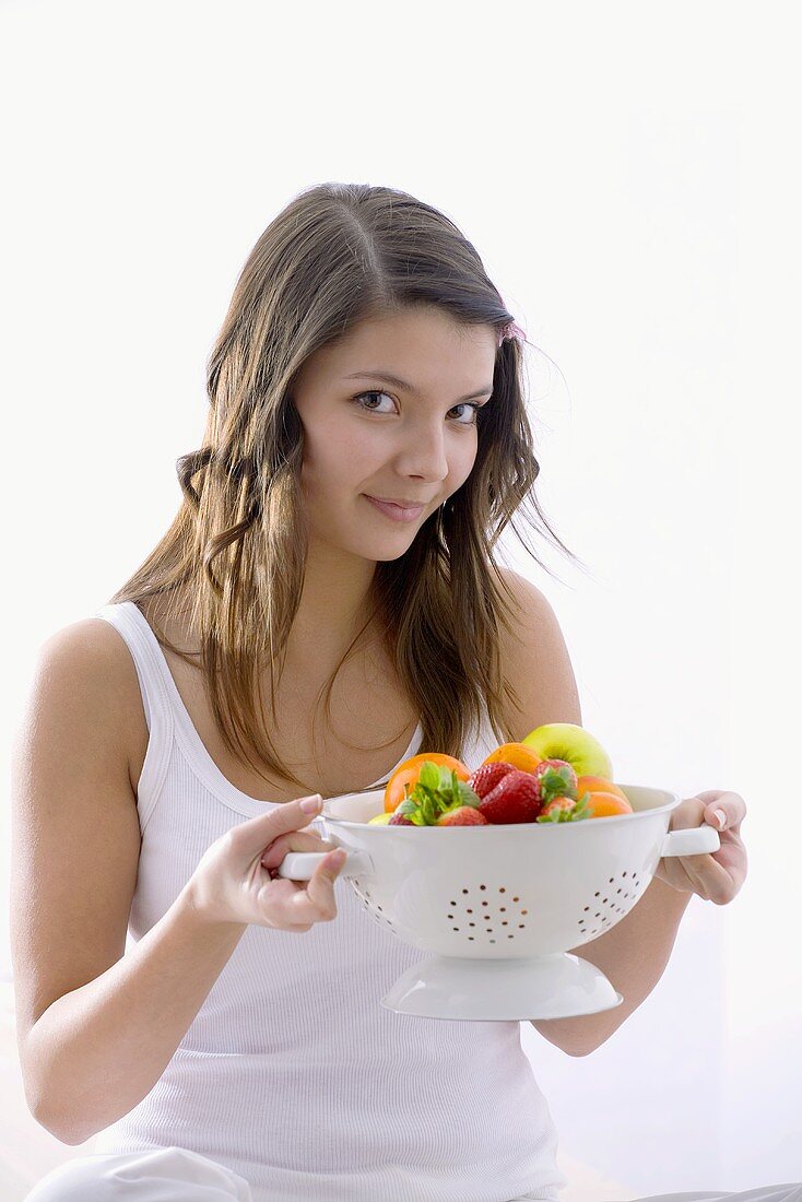 Mädchen hält Küchensieb mit frischem Obst