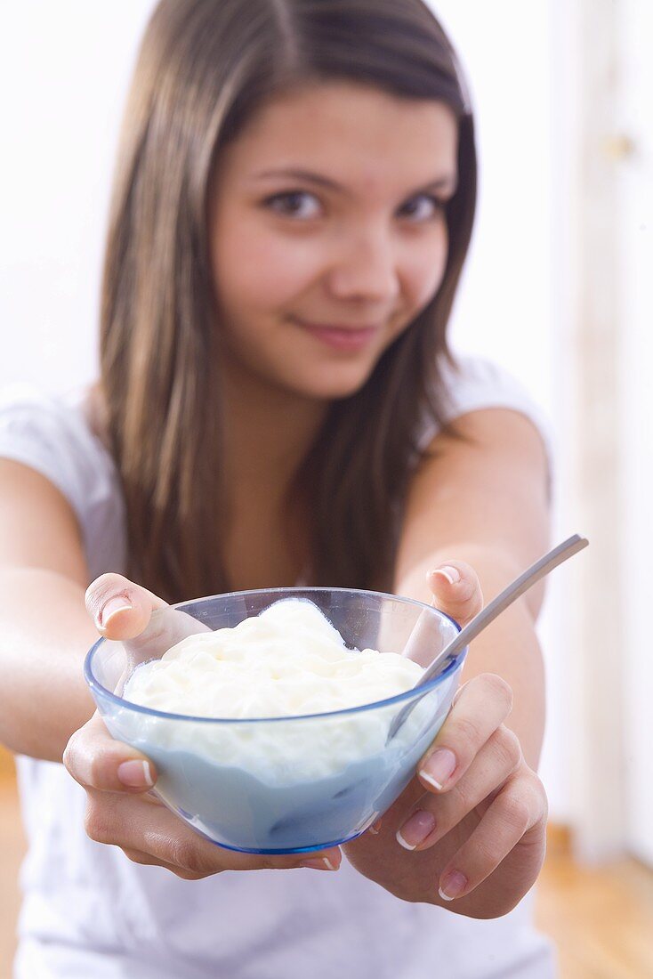 Mädchen hält Glasschale mit Joghurt