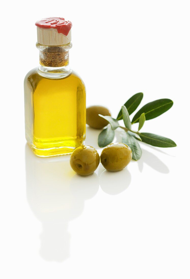 A small bottle of olive oil with olives and olive sprig