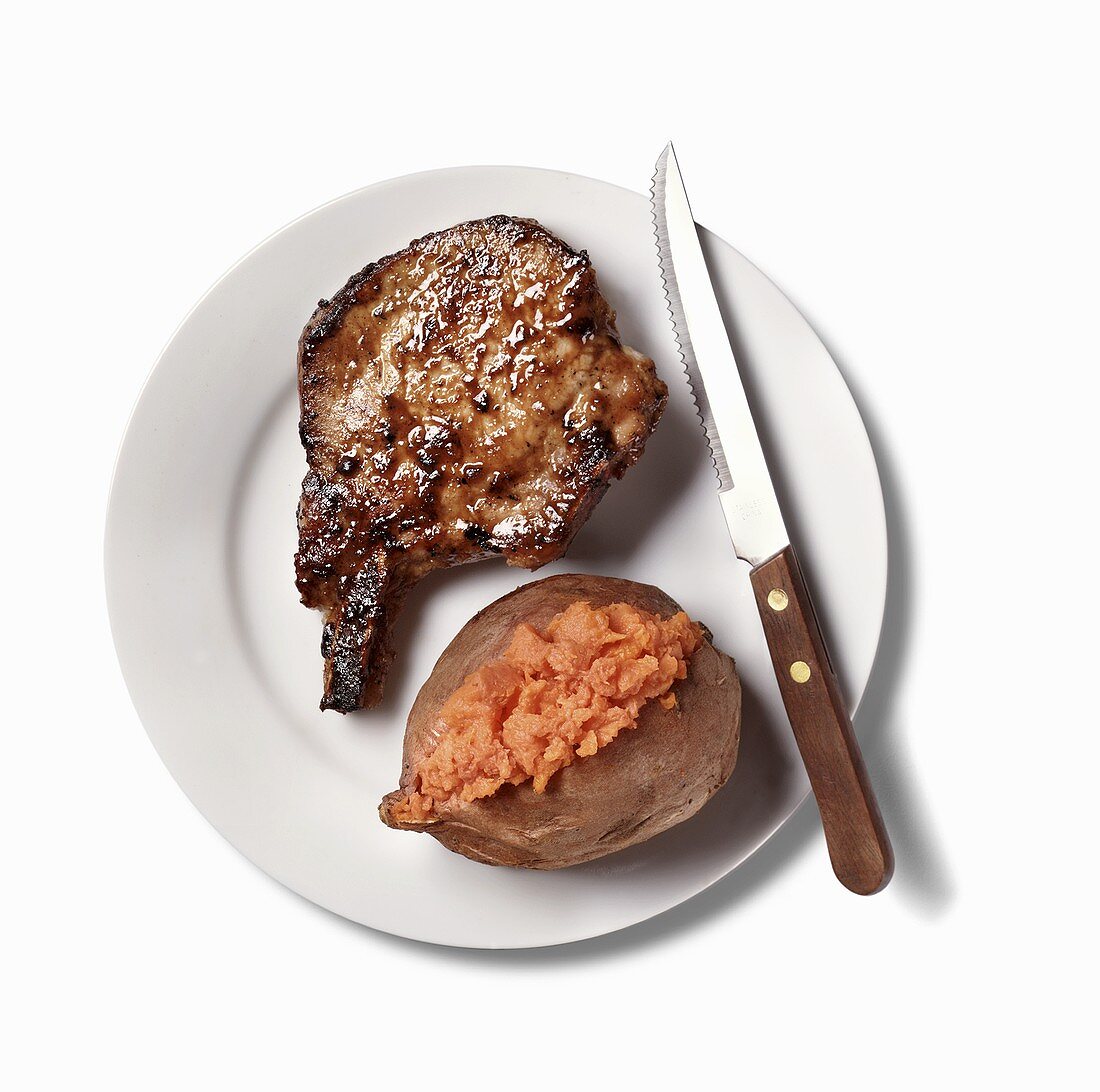 Pork Chop and Baked Sweet Potato on White Plate; White Background