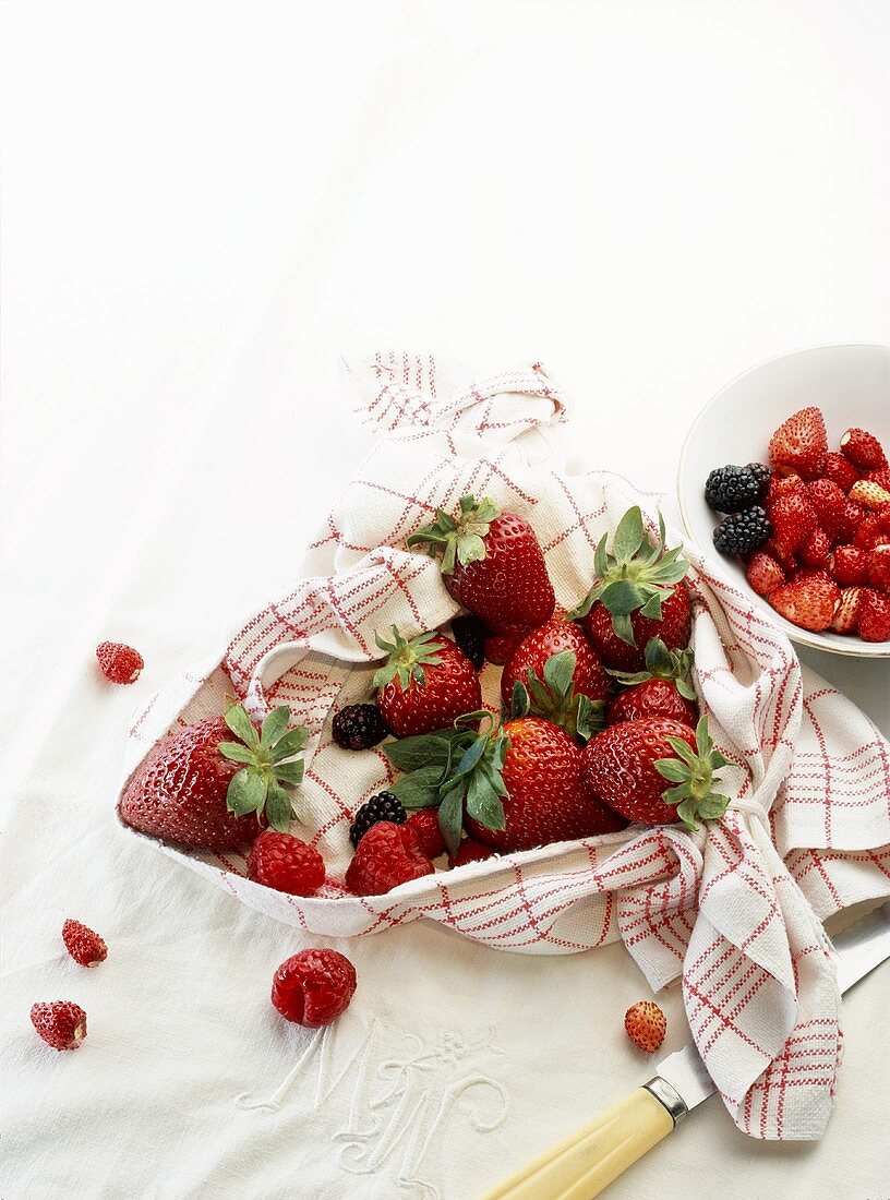 Fresh berries in a kitchen towel and in a bowl