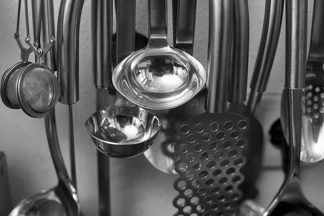Different kitchen utensils hanging from hooks in a kitchen