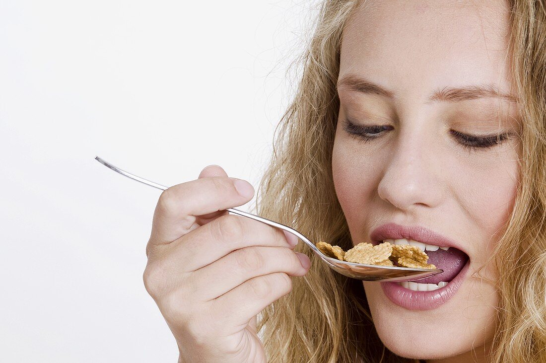 Young womand eating cornflakes from a spoon