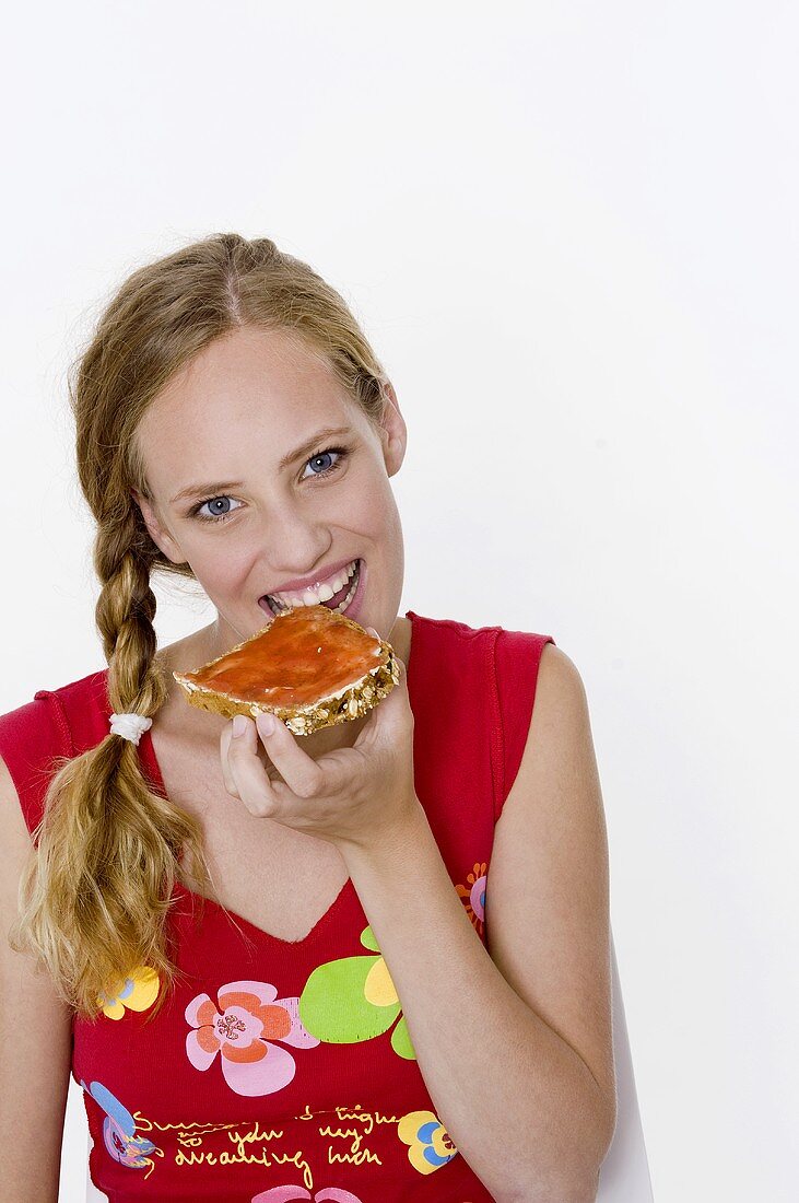 Woman biting into a slice of bread with jam