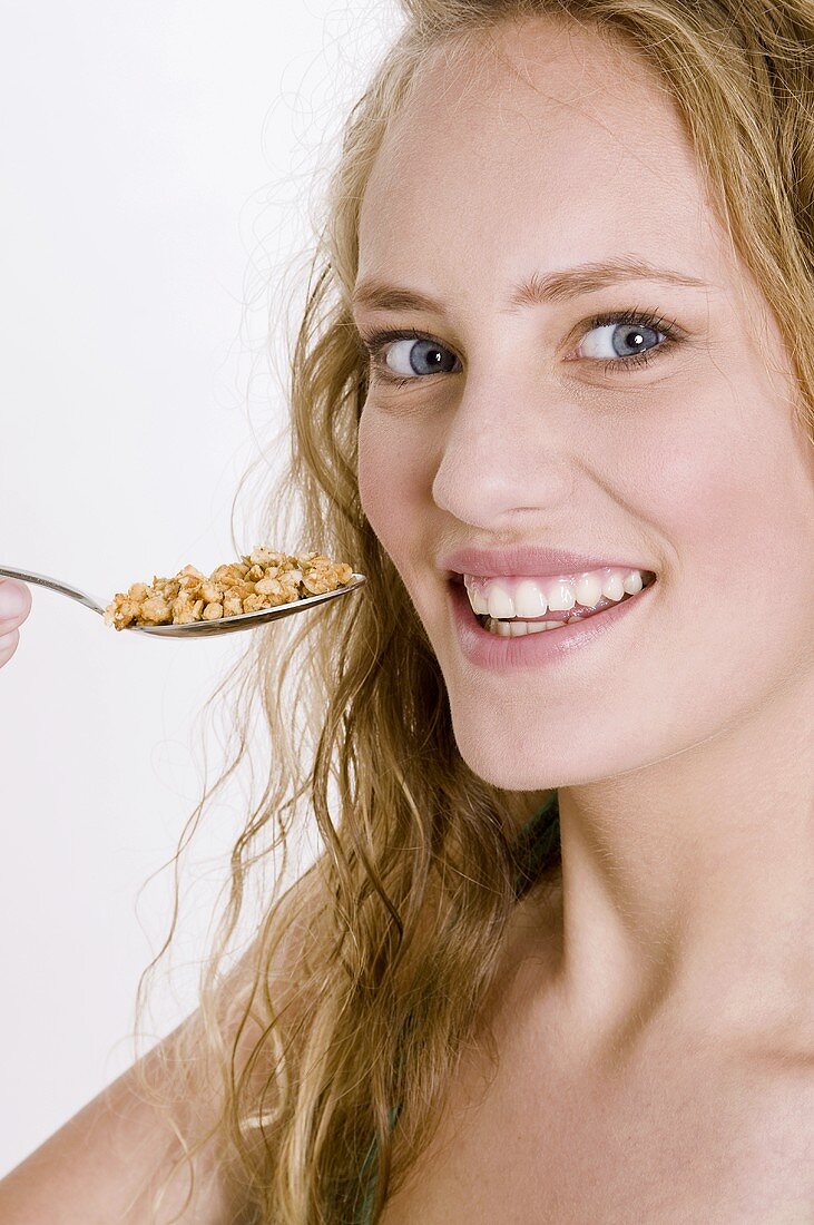 Young woman eating crunchy muesli