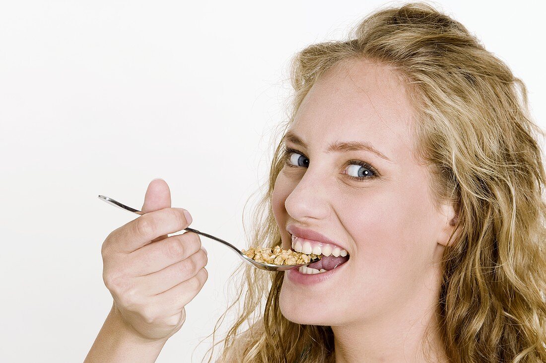 Young woman eating crunchy muesli with a spoon