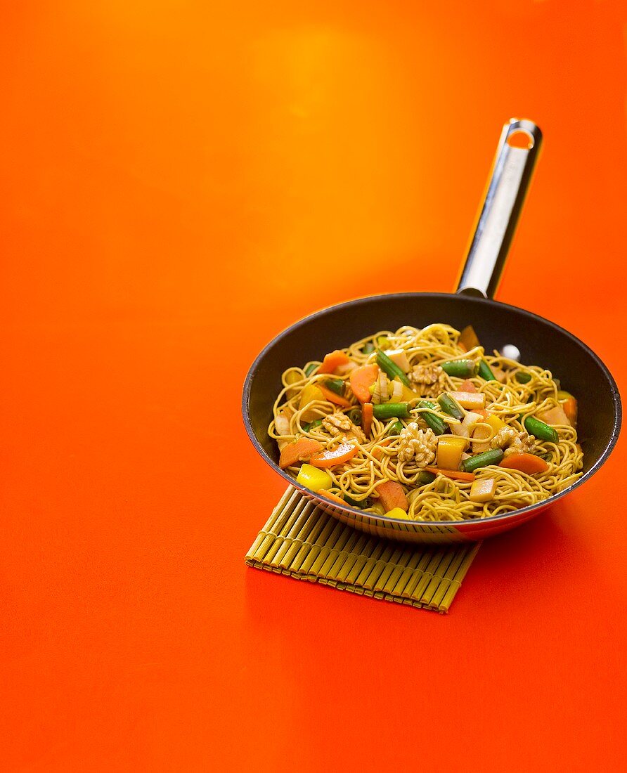 Vegetable chop suey with noodles and walnuts in frying pan