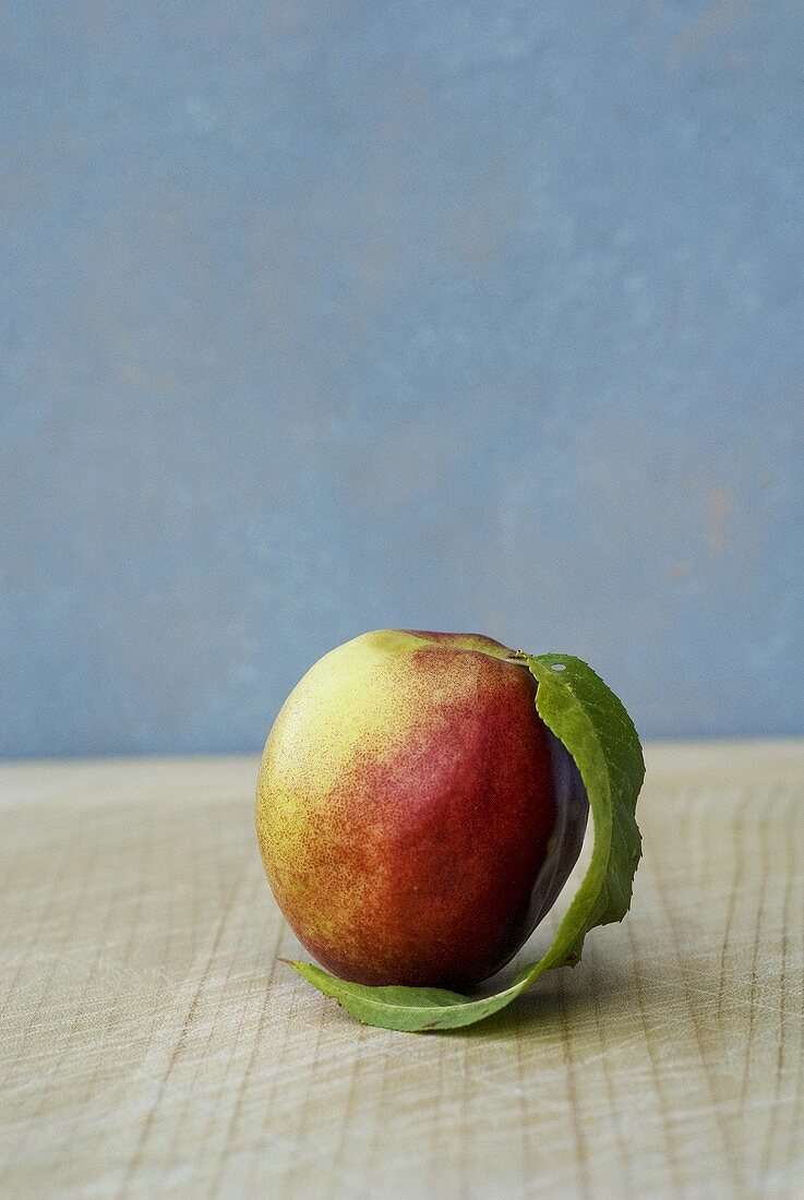 A nectarine with leaf on wooden background