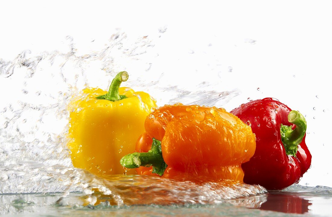 Peppers (yellow, orange, red) with splashing water