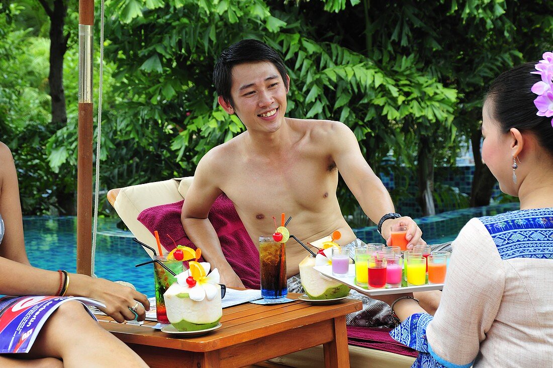 Woman serving cold, exotic fruit drinks by pool
