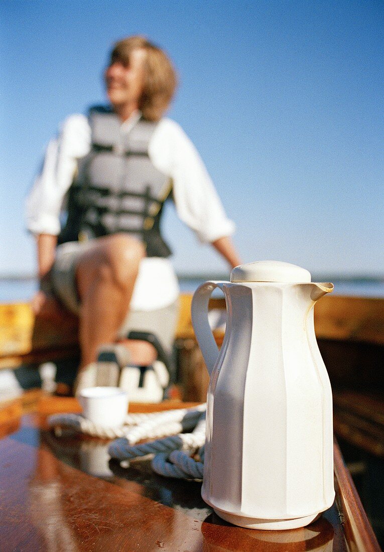 Thermoskanne auf einem Boot, Frau im Hintergrund