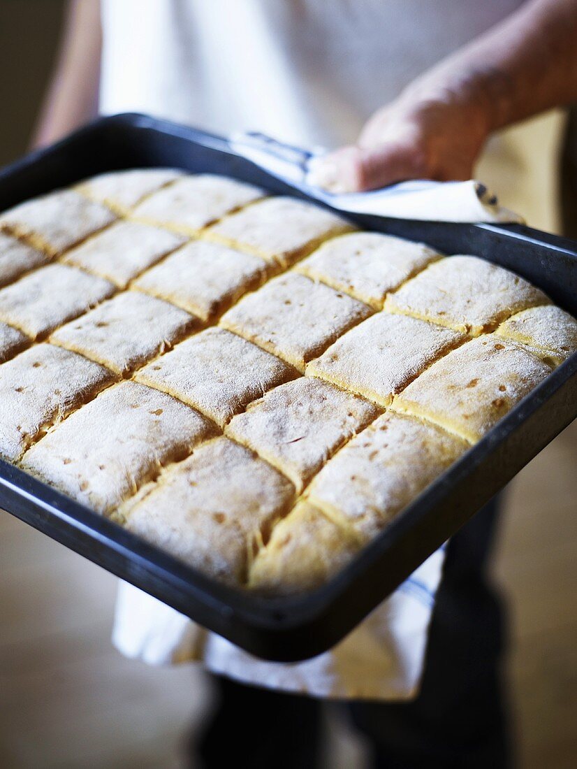 Baker holding a tray of buns