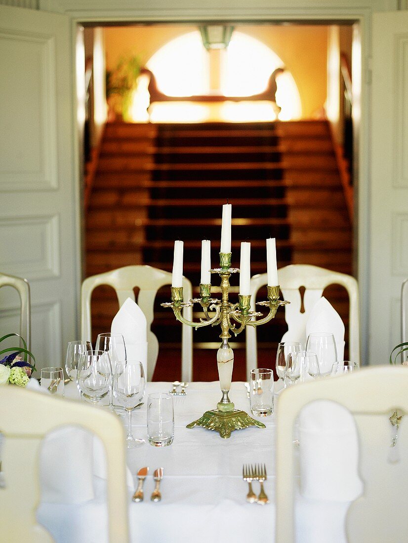 Herrschaftlicher Treppenaufgang; davor ein fürstlich gedeckter Tisch mit edlem Kerzenleuchter
