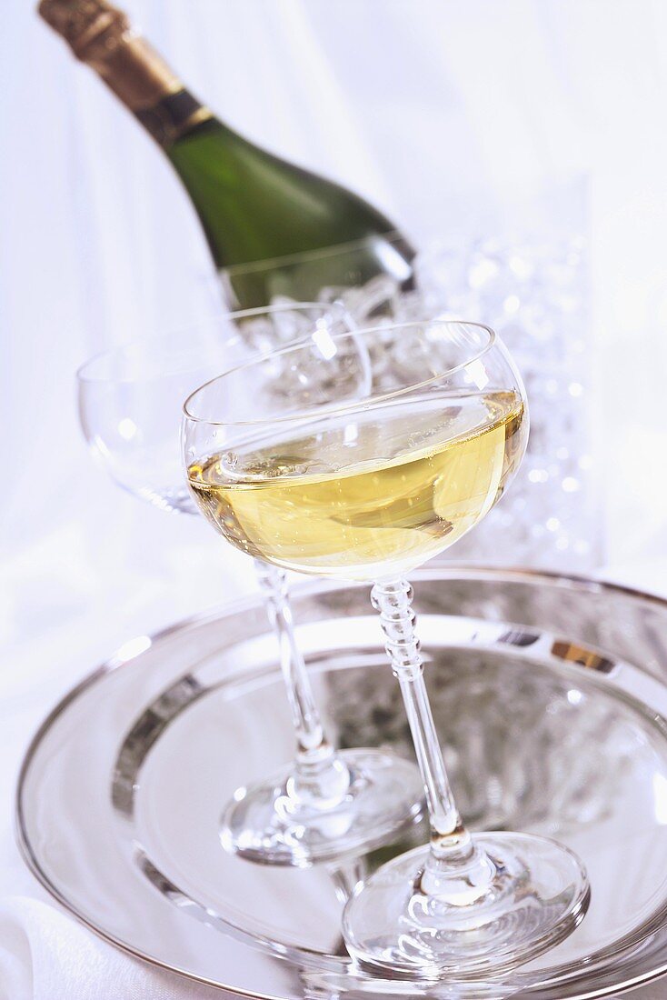 Champagnerglas auf Tablett, Flasche im Hintergrund