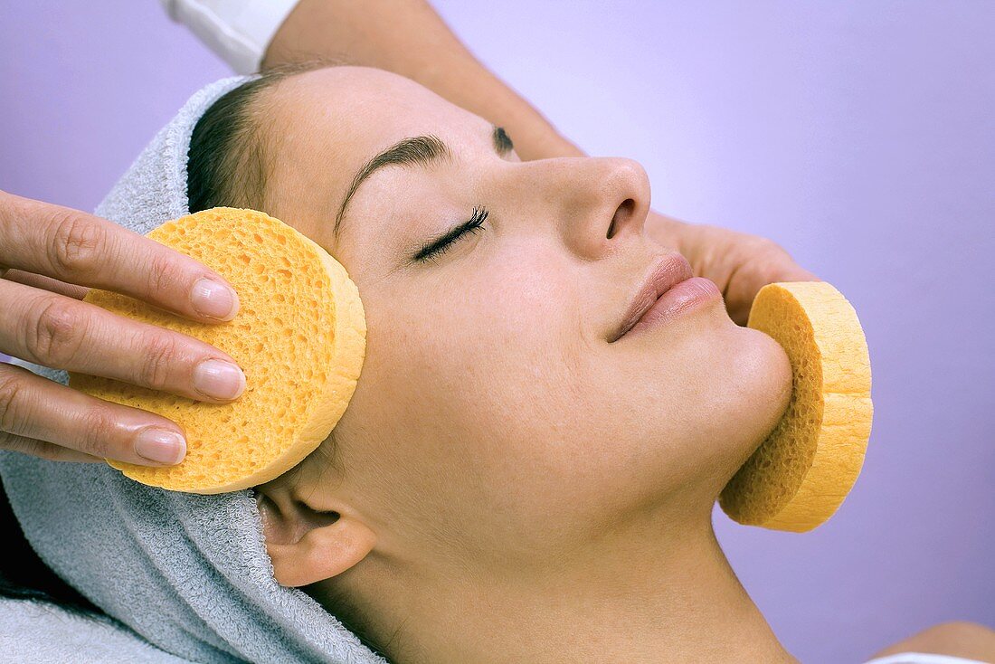 Young woman receiving facial massage, close-up