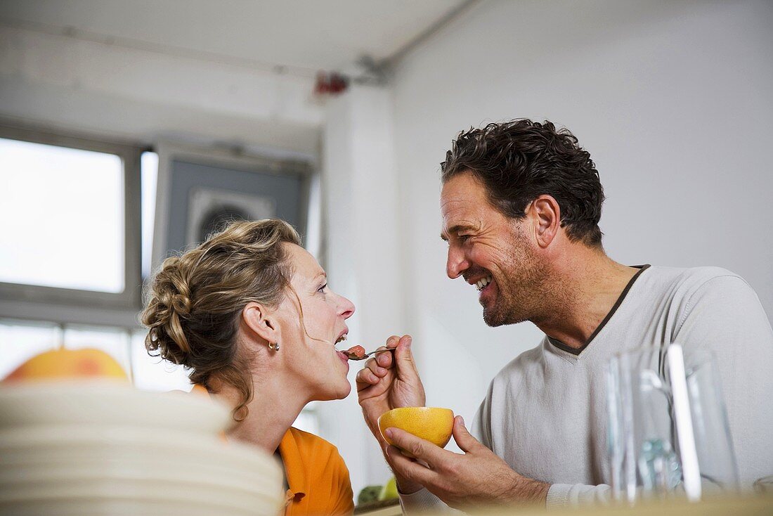 Mann füttert Frau mit Grapefruit