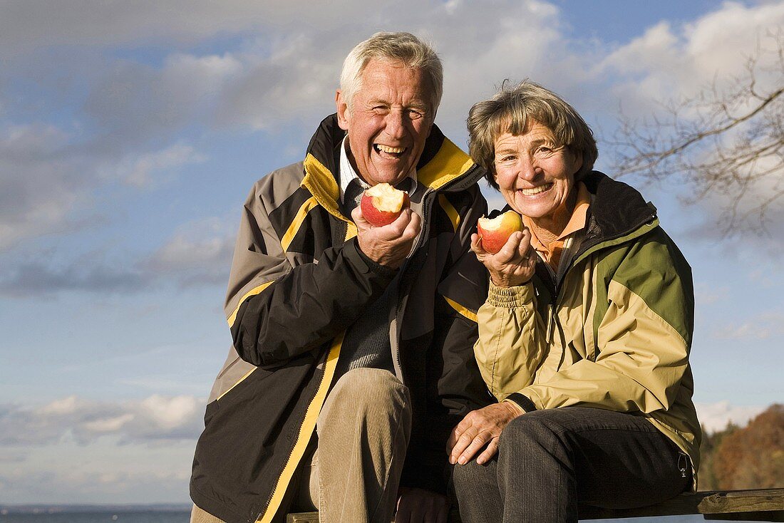 Senior couple eating apples out of doors