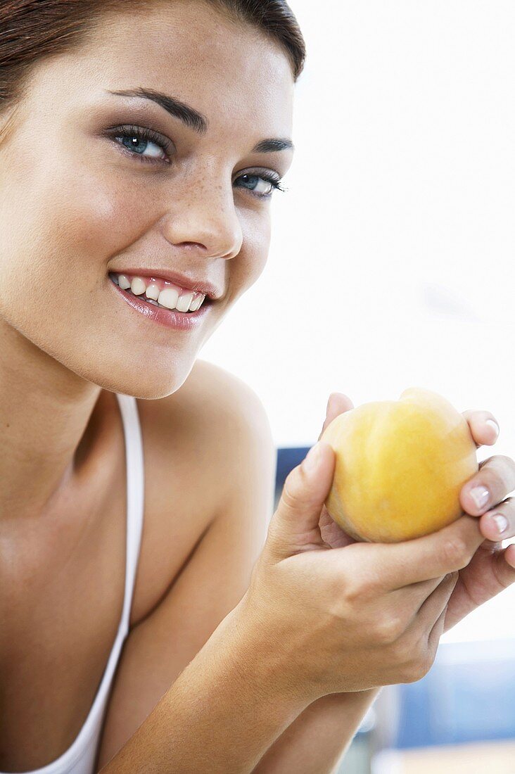 Junge Frau hält einen Pfirsich