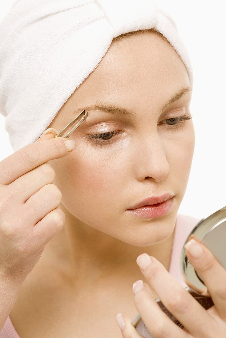 Young woman tweezing her eyebrows, portrait