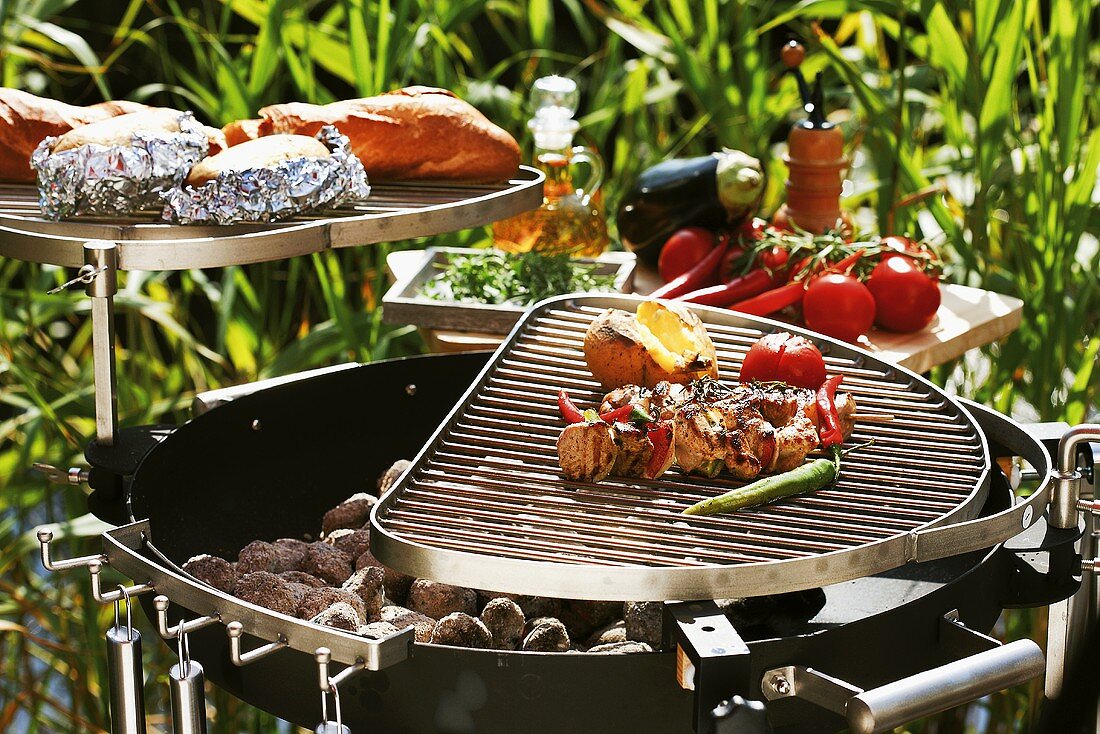 Barbecuing out of doors (kebabs, vegetables, potatoes, baguette)