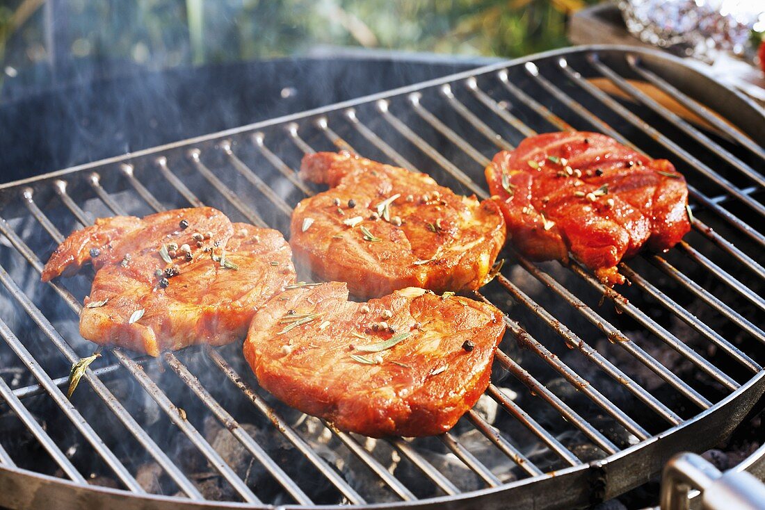 Marinated pork neck steaks on barbecue