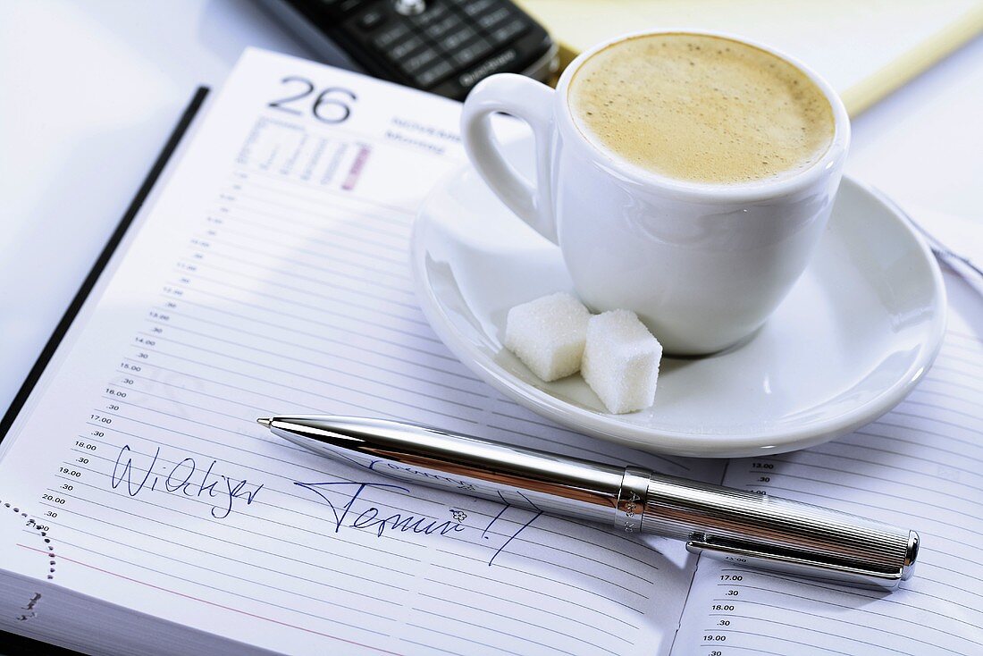 Cup of coffee on a diary, ball-point in front