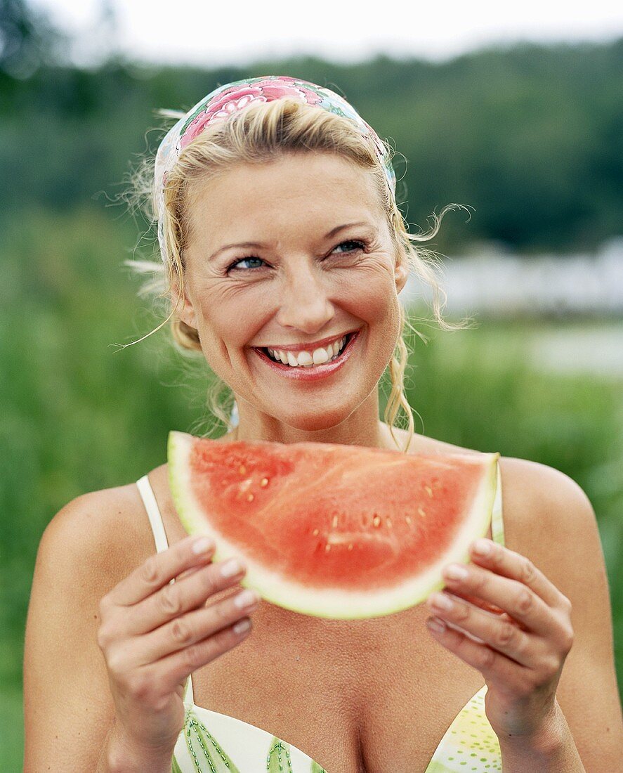 Lächelnde Frau mit einem Stück Wassermelone