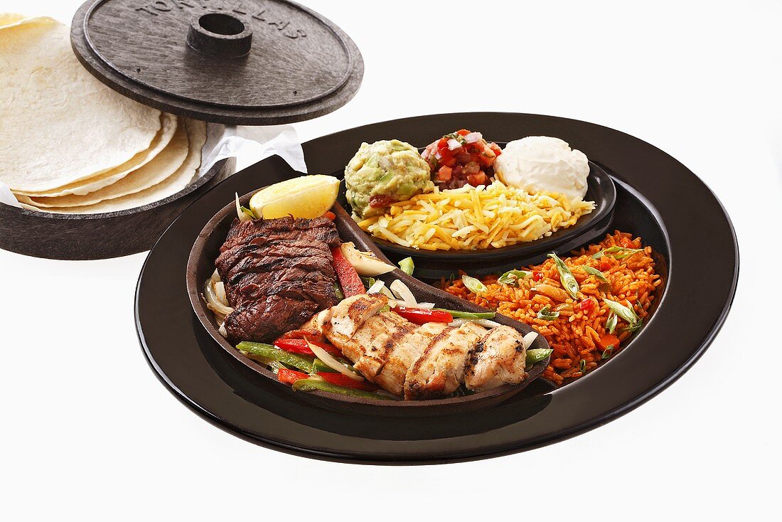 Chicken and beef fajita with accompaniments and tortillas