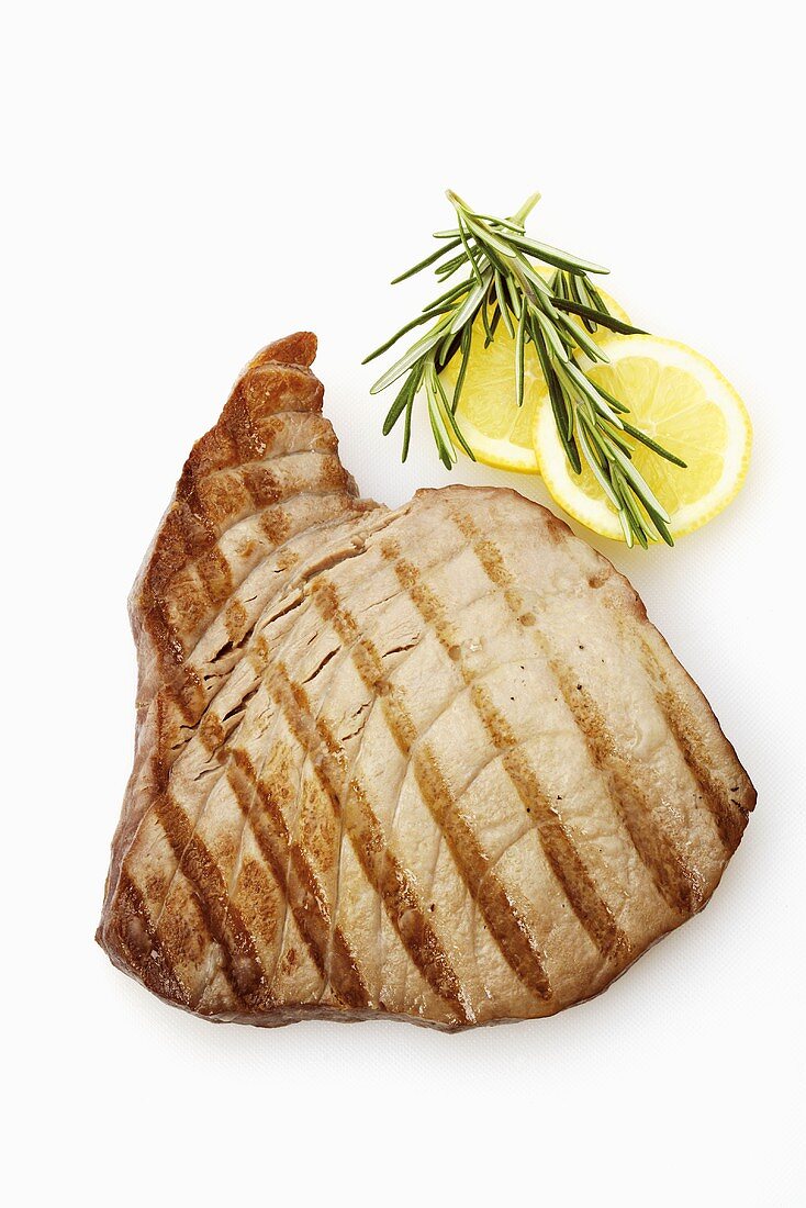 Grilled tuna steak, lemon slices and rosemary (overhead)