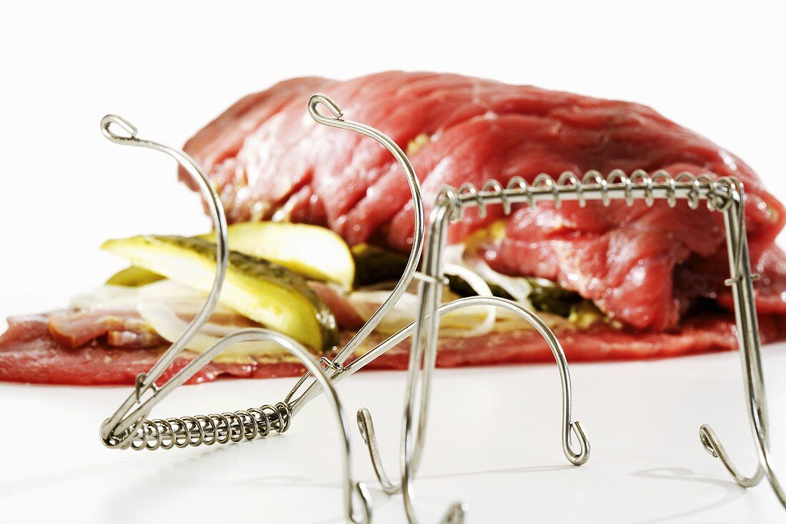 Raw beef roulade with metal clamp