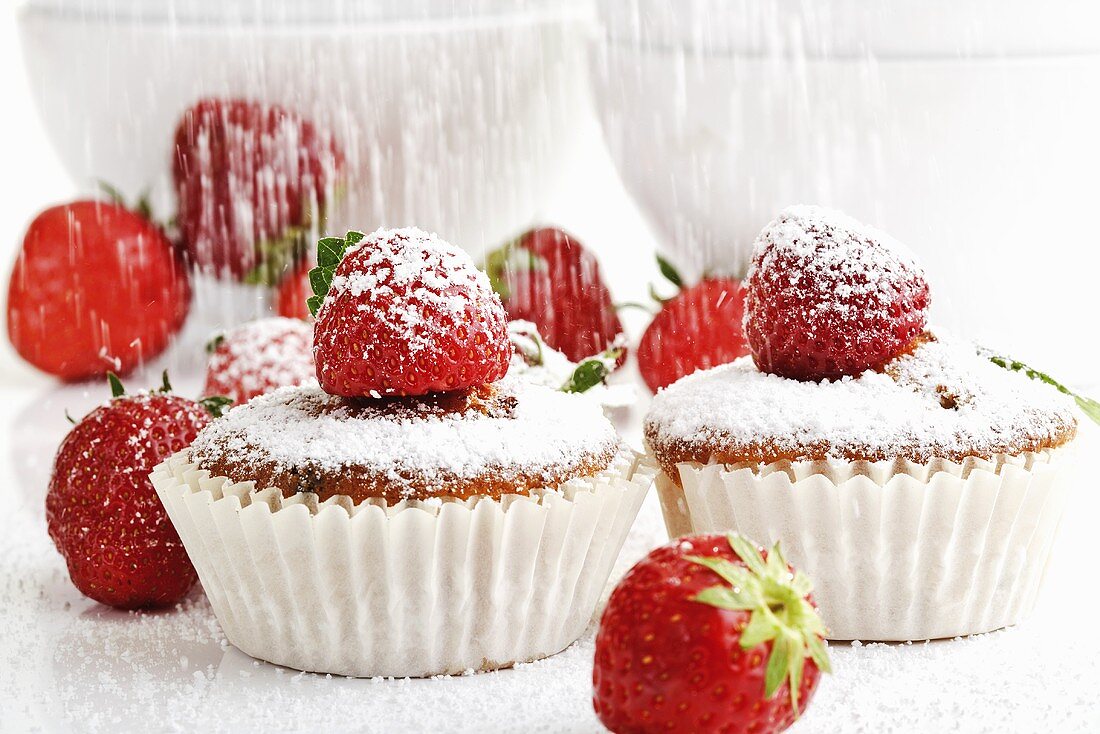 Sprinkling strawberry muffins with icing sugar