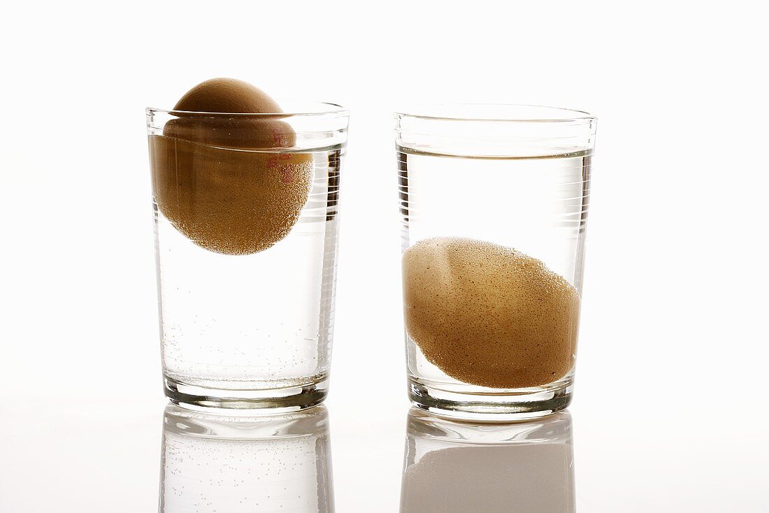 Two eggs in glasses of water (freshness test)