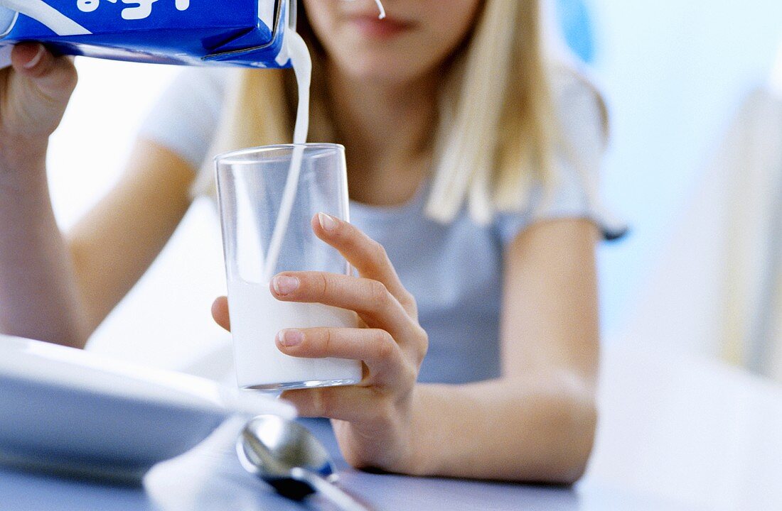 Mädchen giesst Milch in Glas