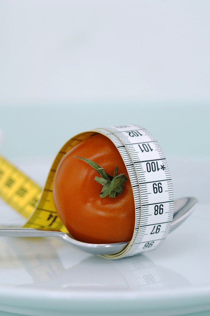 Tomate auf Löffel, mit Massband umwickelt