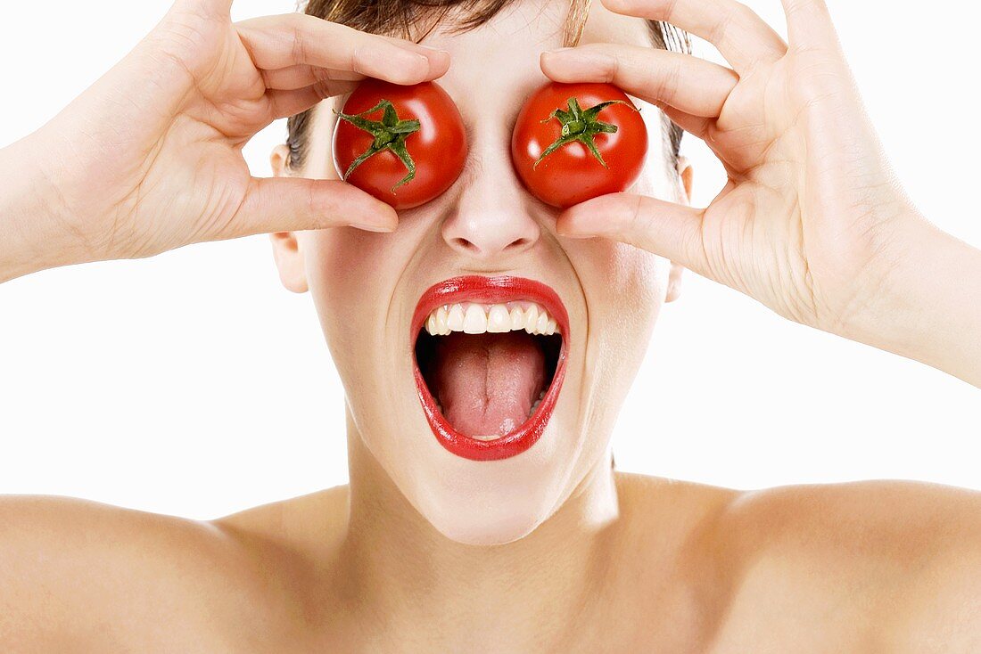 Junge Frau hält sich zwei Tomaten vor die Augen