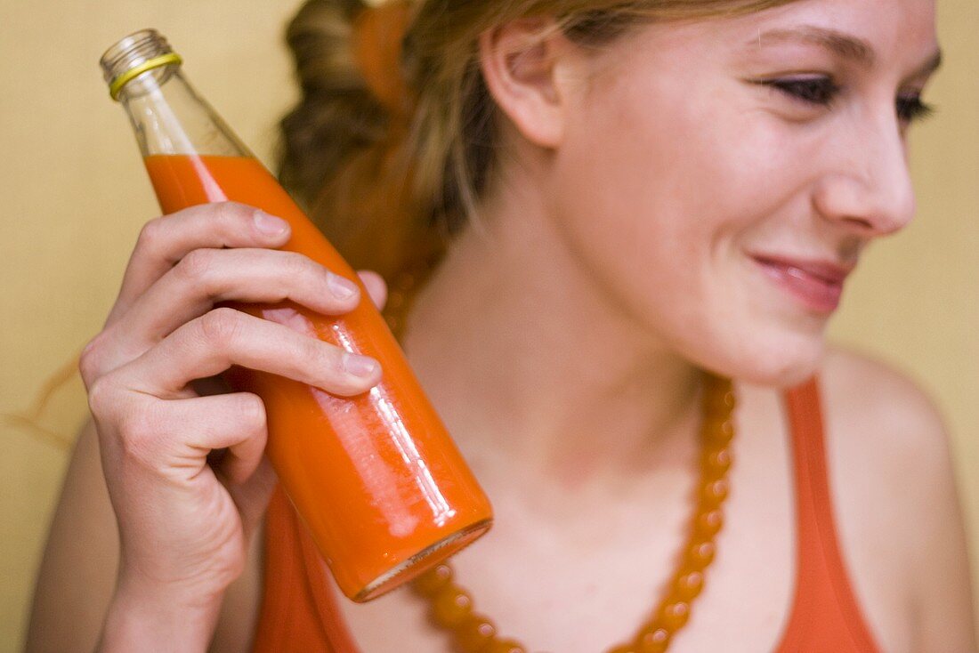 Frau mit einer Flasche Karottensaft
