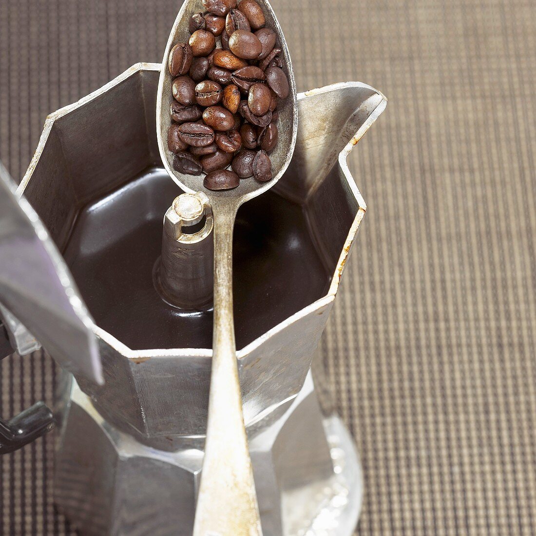 Espressokanne und Löffel mit Kaffeebohnen