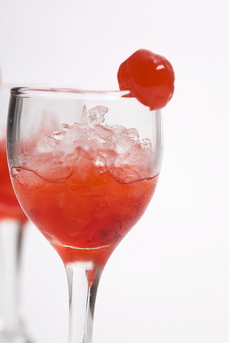 Red cocktail with crushed ice and cocktail cherry