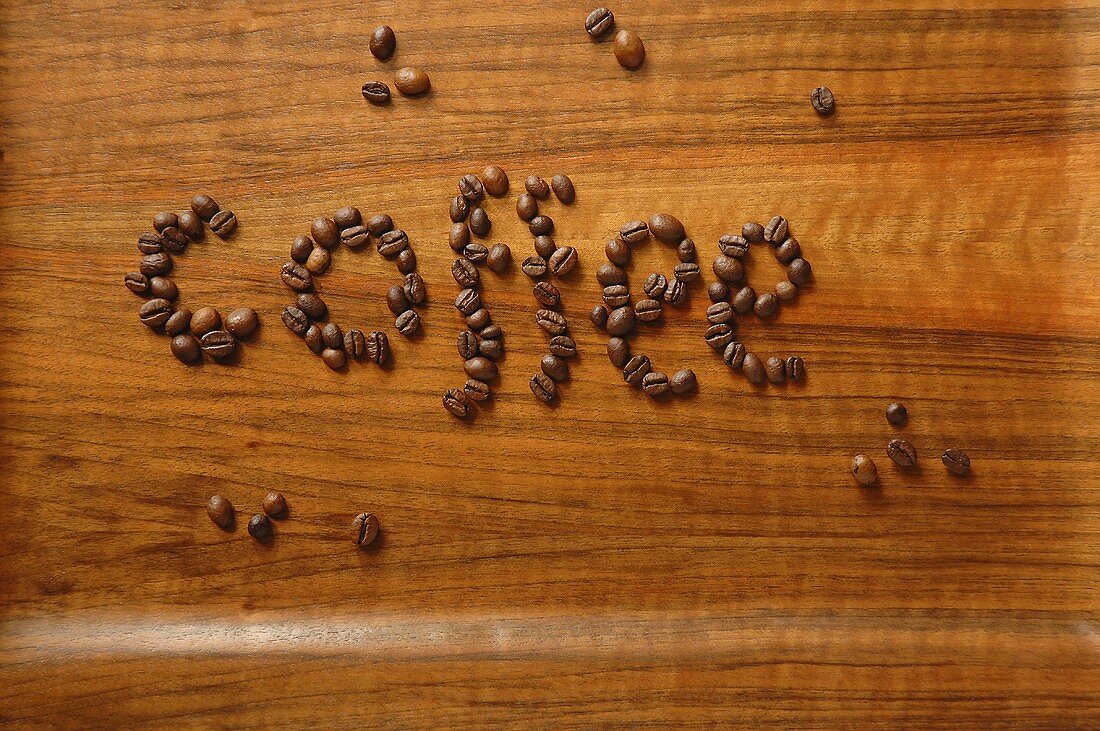 The word 'coffee' written in coffee beans on wooden background