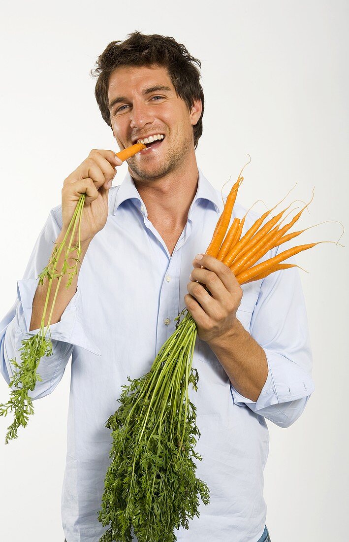 Junger Mann isst Karotte