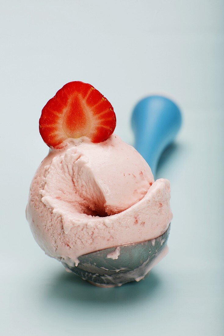 Scoop of strawberry ice cream on ice cream disher, close-up
