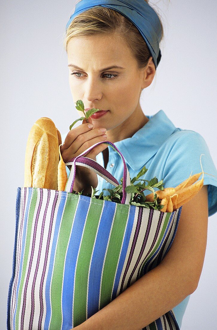 Woman carrying shopping bag with baguette and vegetable