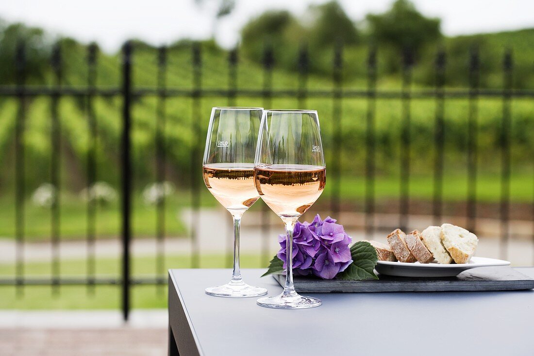 Two glasses of rosé wine, vineyard in background